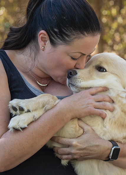 A woman kissing a puppy